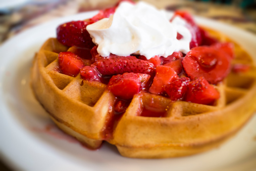 Whipped cream with strawberries on a waffle.