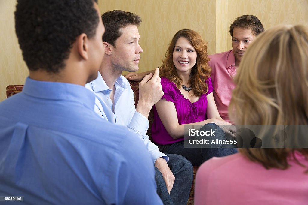 Grupo de adultos hablando en el sofá en la sala de estar - Foto de stock de 20 a 29 años libre de derechos