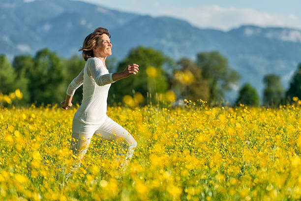 feliz mulher madura flor no prado em - running women jogging profile imagens e fotografias de stock