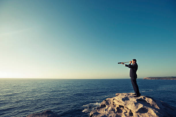 Businessman looking to the future Businessman looking to the future with telescope over the ocean headland photos stock pictures, royalty-free photos & images