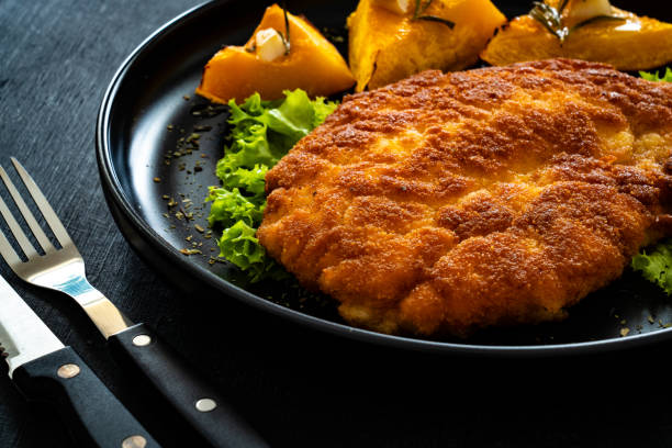 istock Breaded fried pork chop with baked pumpkin on wooden table 1808247685