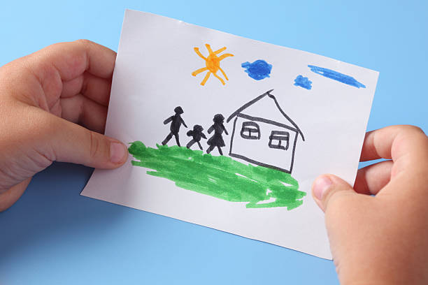 istock Child holds a drawn house with family 180824775
