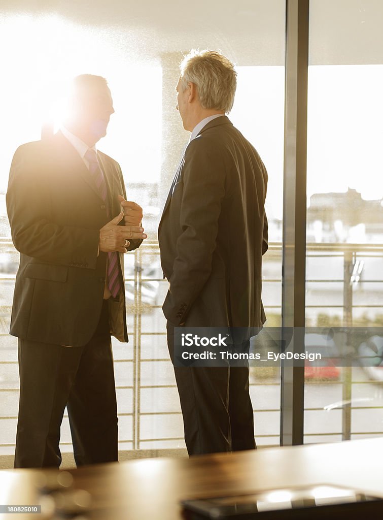 Two Businessmen talking in a business meeting "Two businessmen in a late afternoon business meeting. Sun flares in the background, Vertical shot." Manager Stock Photo