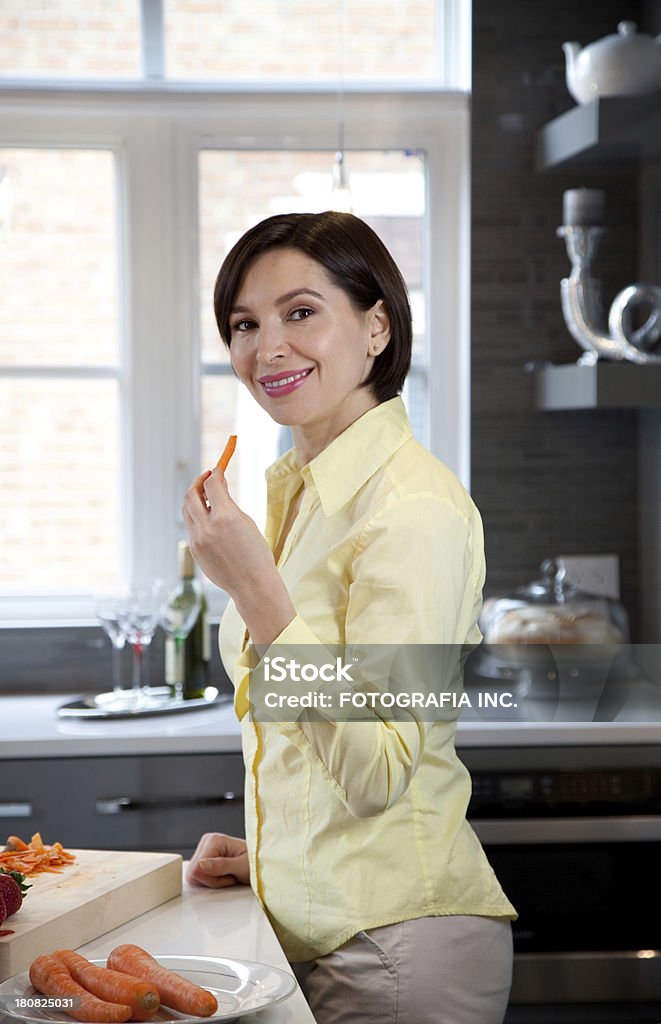 Young woman in the kitchen "Young Caucasian woman in her new new luxury kitchen.Objects on the wall shelf are not copyright pieces of art, but ordinary furniture store prop." Adult Stock Photo