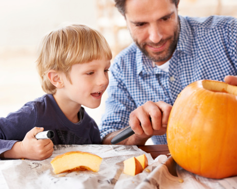 A father and son carving a pumpkin in the kitchen for halloween
