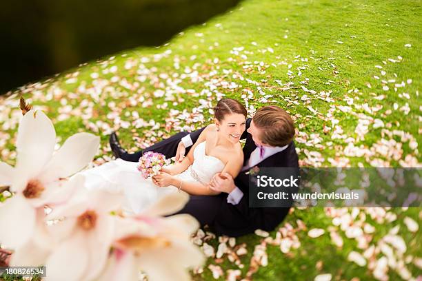 Foto de Noiva E Noivo Sentado No Parque Com Árvores De Magnólia e mais fotos de stock de Bouquet