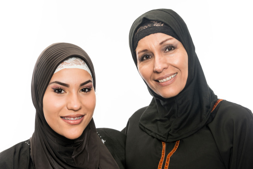 Smiling mature muslim woman posing with her daughter on white background