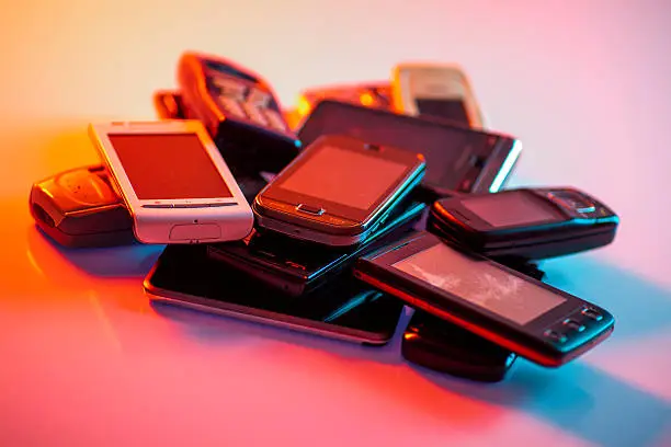 Old used cellphones pile under mixed lights