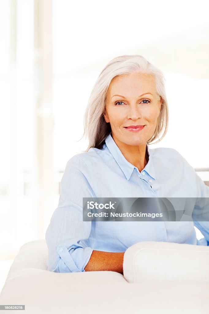 Senior donna seduta su un divano - Foto stock royalty-free di 60-69 anni