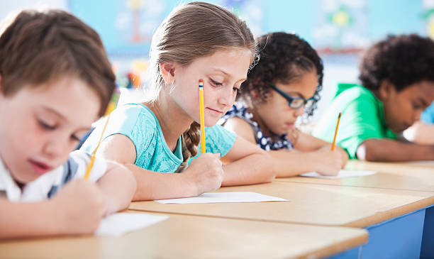 école élémentaire des enfants en classe d'écriture - schoolgirl little girls crayon human face photos et images de collection