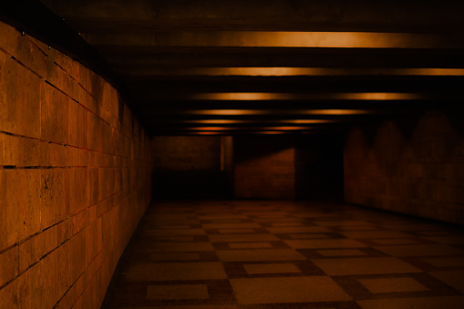 Urban background of a dark underground passage lighted by distressing red lamps