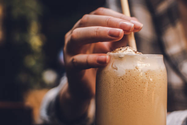 istock Ice latte background. Girl drinking coffee and holding a straw between her fingers 1808293868