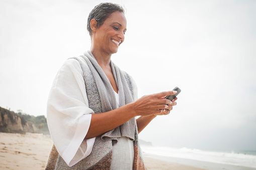 African American Woman Checking Smartphone on Beach