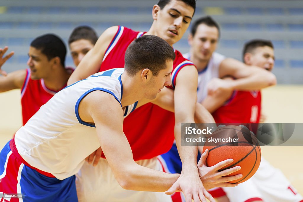 Group of basketball players in action. Young basketball player is holding the ball and trying not to allow the other player take the ball. Basketball - Ball Stock Photo