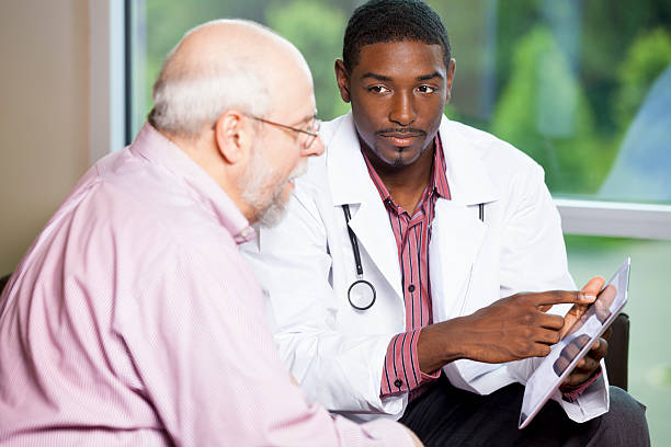 istock Senior man looking at information on digital tablet with doctor 180830640