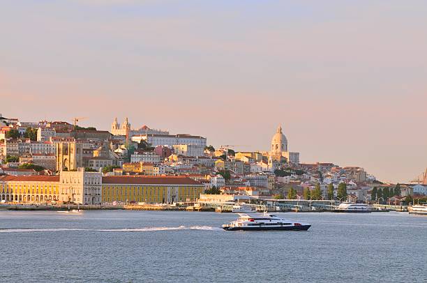 Lisbon Ferry And Alfama Cityscape A sunset view of the Alfama district in Lisbon with the National Pantheon, the monastery of So Vicente de Fora and finally the Riberia Palace on Commerce Square next to the Tagus river. What a value, all that history in one shot. national pantheon lisbon stock pictures, royalty-free photos & images