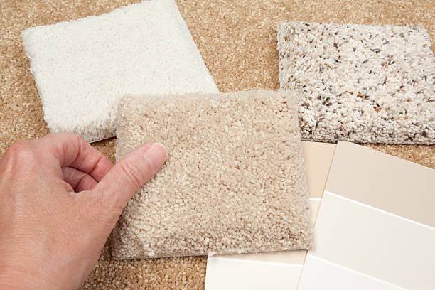 Home Decorating:  Choosing Beige Carpet "Close-up of a woman's hand touching a plush beige carpet sample, More beige carpet samples and color swatches are in the background.Please also see my Home Improvement Lightbox:" carpet sample stock pictures, royalty-free photos & images