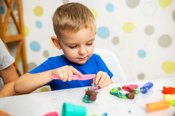 istock Little boy enthusiastically plays with plasticine, play dough on white table 1808329633