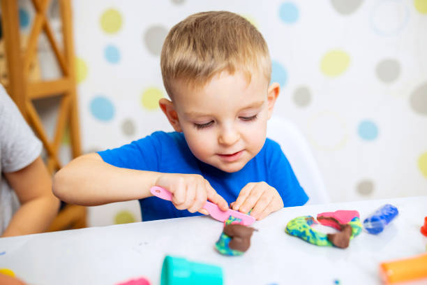 istock Little boy enthusiastically plays with plasticine, play dough on white table 1808330143