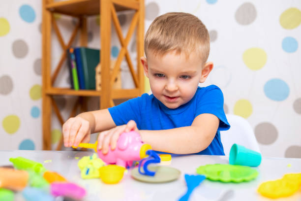 istock Little boy enthusiastically plays with plasticine, play dough on white table 1808330146
