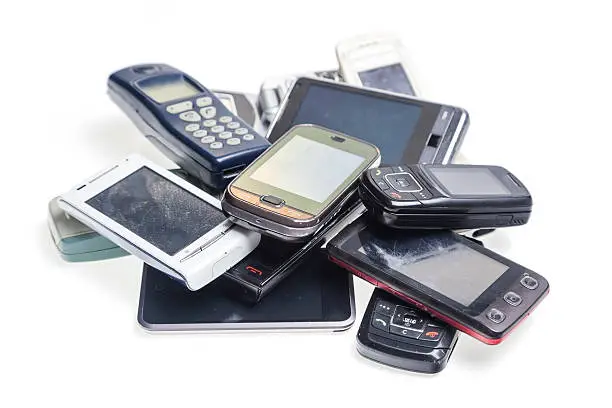 Old used cellphones pile over white