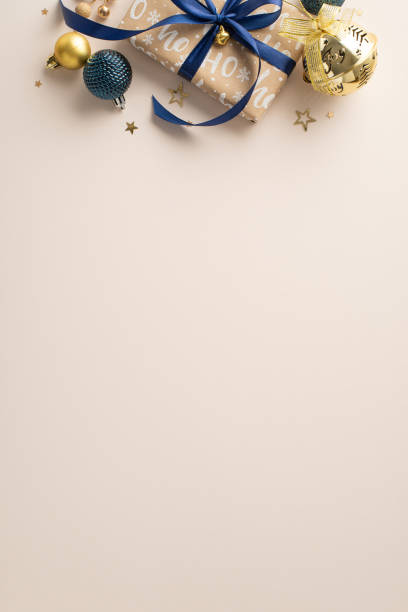 istock Chic Holiday Ensemble: Top view vertical composition featuring craft gift box, stylish baubles, and glittering star shaped confetti on pastel beige backdrop. Great choice for New Year greetings or ads 1808334395