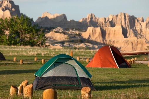 Tents stand in the Cedar Pass Campground with the eroded landscape of South Dakota's Badlands National Park in the background.