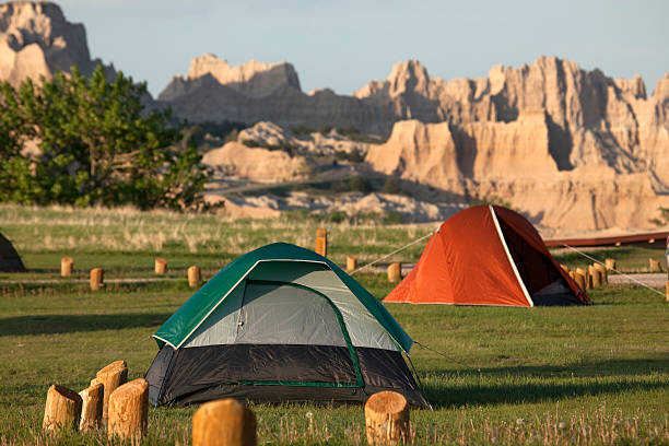 Camping Badlands National Park South Dakota Tents stand in the Cedar Pass Campground with the eroded landscape of South Dakota's Badlands National Park in the background. badlands stock pictures, royalty-free photos & images