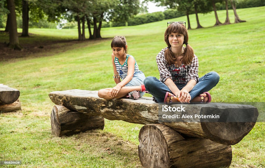 Zwei Schwestern sitzt auf der Parkbank - Lizenzfrei 10-11 Jahre Stock-Foto