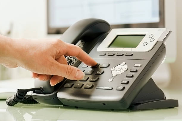 istock Hand dialing number on business telephone 180834611