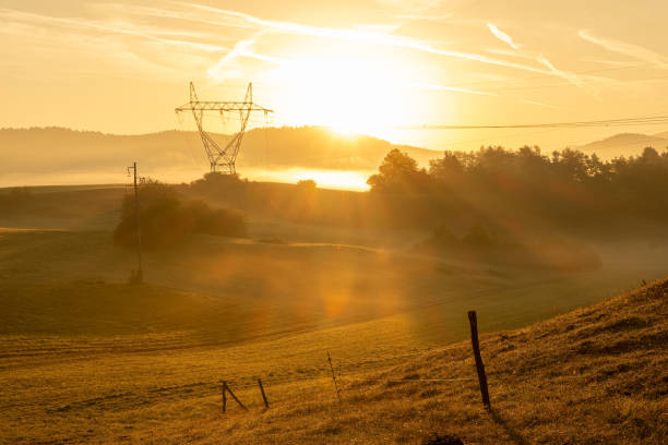 istock Sunrise over yellow meadows and powerline tower 1808346870