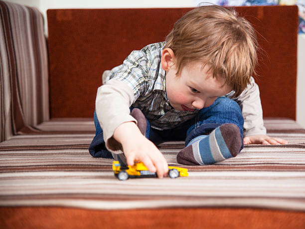 istock Little boy leaning over playing with a toy car 180834799