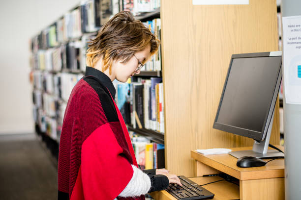 adolescente navega por la información en la computadora de la biblioteca - university of manitoba fotografías e imágenes de stock