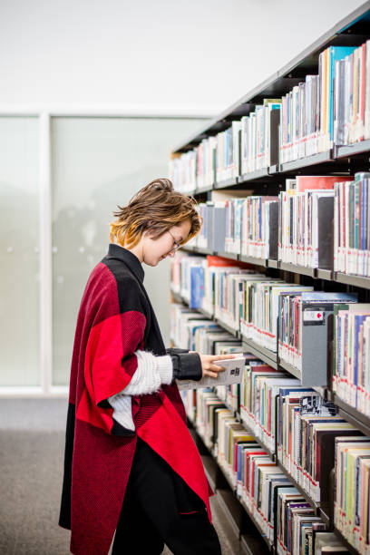 moderne identität: gender-nonkonformer teenager erkundet die bibliothek - canada manitoba university winnipeg stock-fotos und bilder