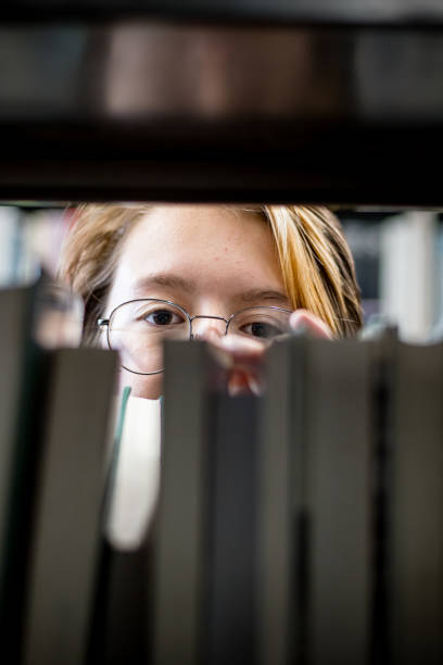 literary wonderland: teen's radiant expression amidst a world of books - university of manitoba imagens e fotografias de stock