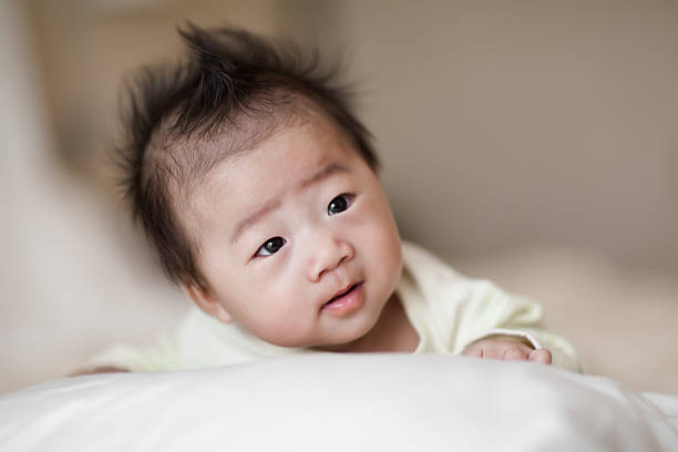 Sweet little baby boy crawling on white bed stock photo