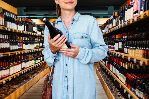 konsumentka kupująca wino w sklepie monopolowym. - wine bottle liquor store wine variation zdjęcia i obrazy z banku zdjęć