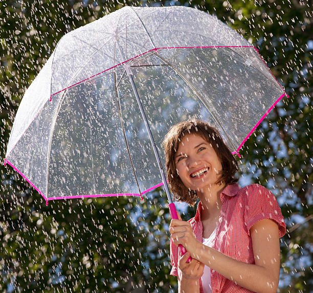 istock Playful young woman holding umbrella 180837730