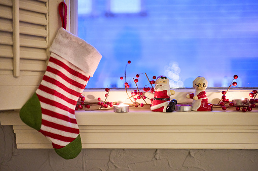 Christmas stocking and decorations sitting on the window sill of a home during the holidays