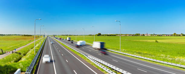 Highway through grassy fields on a sunny day, The Netherlands