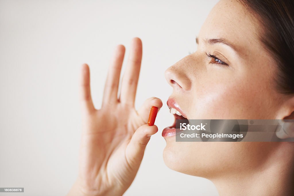 Taking a vitamin supplement Profile of a beautiful young woman about to take a tablet Taking Medicine Stock Photo