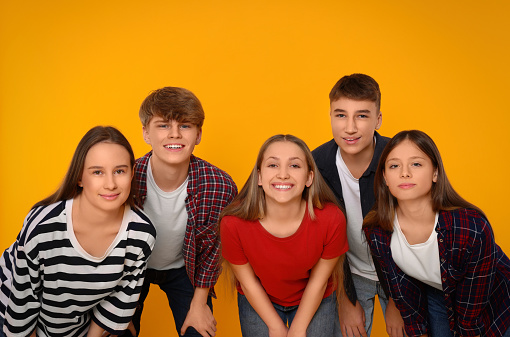 Group of happy teenagers on orange background