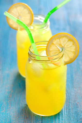 Refreshing lemonade in glass jars on wooden table