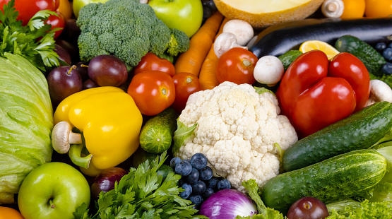 Top view of various multicolored fruits and vegetables disposed side by side at the center of the image on a stripe shape leaving a useful copy space at the top and at the bottom on white background