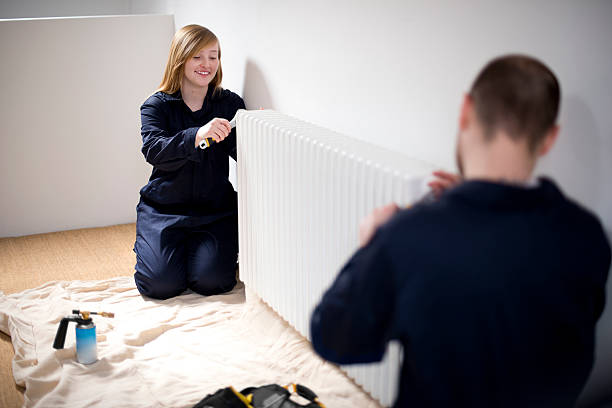 trainee female plumber trainee female plumber fitting a radiator heating engineer stock pictures, royalty-free photos & images