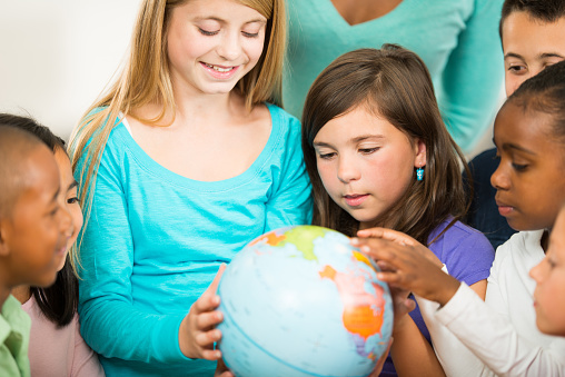 Diverse elementary students looking at a globe