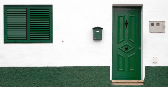 Dark green door and window, white wall.