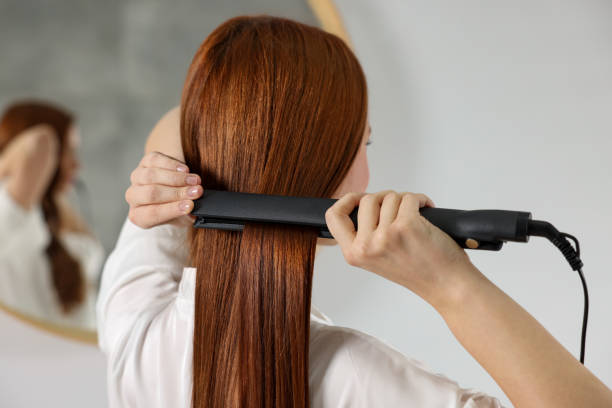 istock Beautiful woman using hair iron in room 1808420783