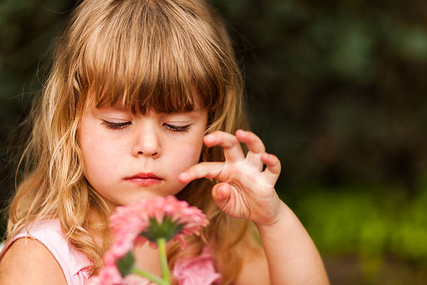 istock Cute girl playing with pink flower 180842269