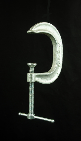 A silver metal clamp on a black background.